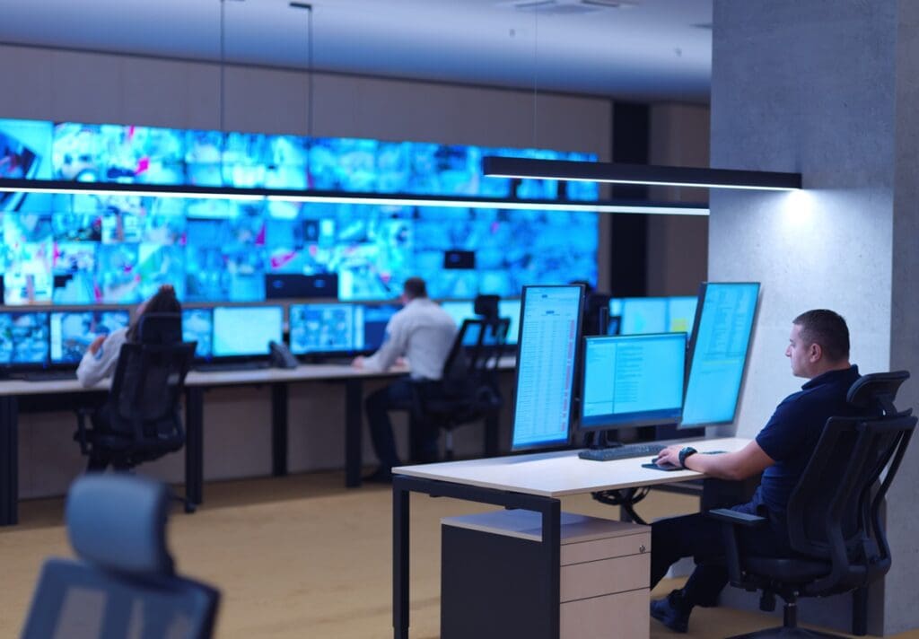 Male security operator working in a data system control room.