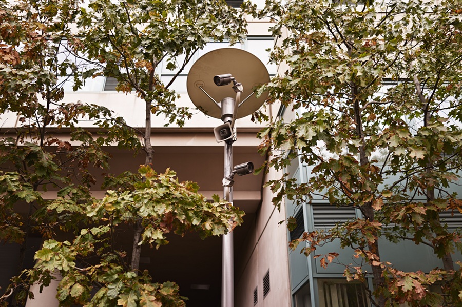 Surveillance cameras on a street light outside an apartment building.