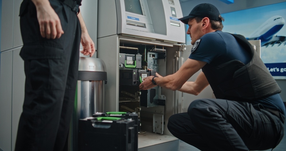 Two security guards with an open ATM machine.