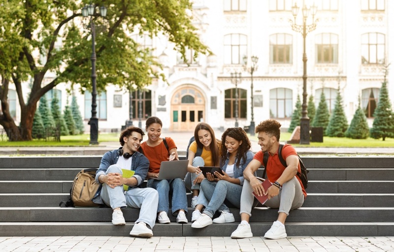 College students sitting on steps on a college campus.