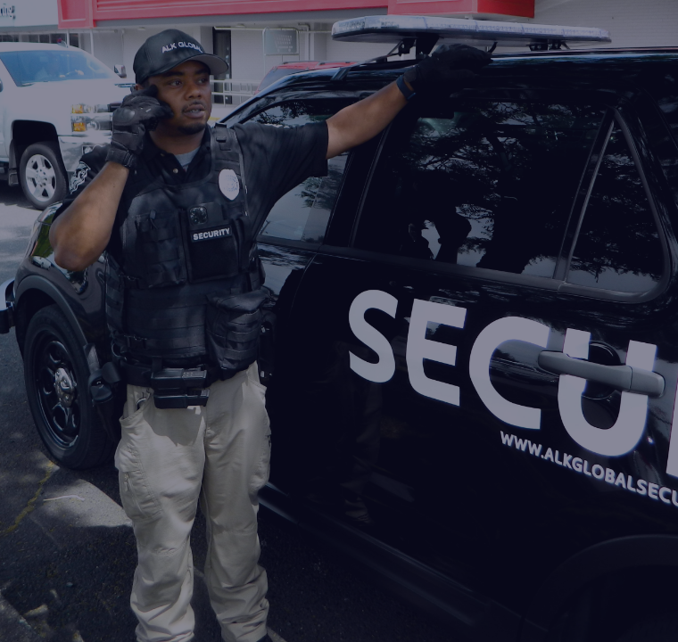 ALK Global Security Guard standing next to patrol car