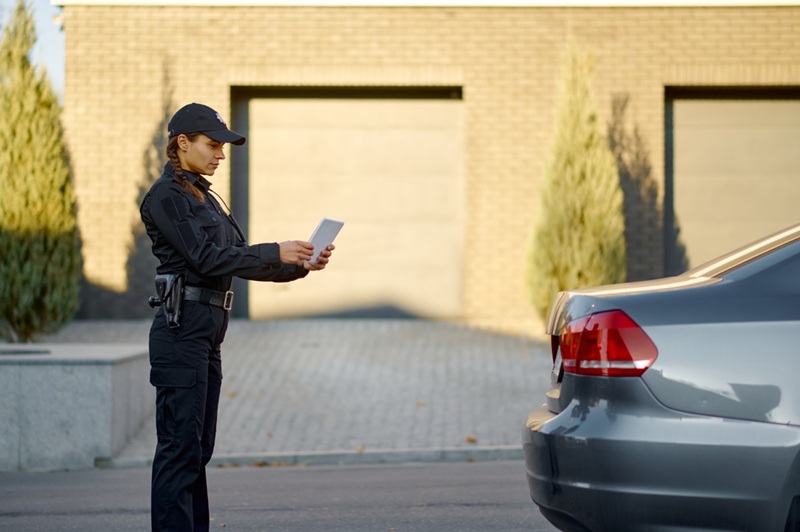 A female security officer examining a license plate.